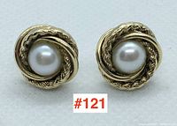 Front view of both stud earrings showing central pearls and twisted gold knot design