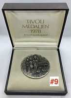 Front view of the sterling silver 1978 Tivoli medallion designed by Jean Philippe Roch inside its original presentation box with lid open showing printed name and date.