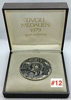 Front view of medallion in presentation box showing silver medallion and interior box text.