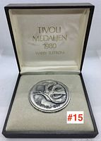 Medallion in original display box showing artist and year markings inside lid.