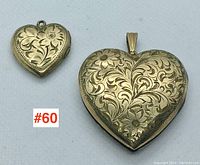 Two heart-shaped gold filled lockets side by side showing engraved floral designs, varying size comparison