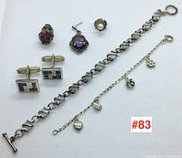 Overview of entire lot including cufflinks, bracelet, anklet, tie tacks, earrings, and ring arranged on white background.