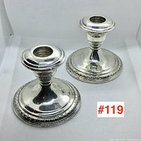 Pair of sterling silver candlesticks shown side by side on white background