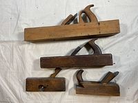 Top view of the 4 wooden block planes laid flat showing the bodies, handles, and blade openings