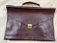 Front view of the burgundy/maroon leather portfolio case showing clasp and handle.