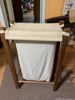 Clothes hamper standing with canvas bag secured inside cedar wood frame.