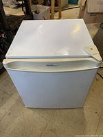 Front view of white Danby mini bar fridge showing single door and handle with slight wear and tear visible.