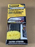 Front of the Meguiar's Headlight Restoration Kit box showing product name, kit contents, and illustrative photos of headlight before and after restoration.