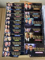 Photo of 21 DVD sets with covers showing characters and titles of Midsomer Murders series arranged in box.