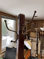 Close-up of metal hooks on the wooden coat rack with rounded ball ends, metal hardware attaching hooks to column.