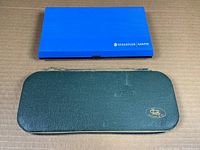 Two closed cases of drafting sets, one blue plastic Staedtler Mars branded, one green zippered leather Anker branded.