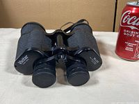 Front view of Vivitar 16x50 binoculars showing brand and magnification details, with a Coca-Cola can for scale.