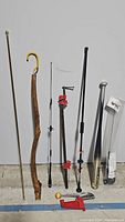 Photo of 6 antennas including telescoping metal antennas, one wooden baseball bat, curtain rod, and several thin rods/tools laid out against a wall