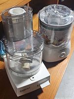 Photo showing Cuisinart food processor and ice cream maker side by side on wooden surface.