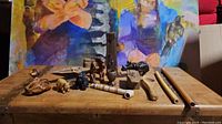 Photo showing multiple carved wood items placed on a wooden surface including animal figures, wooden flute-like items, and wooden box.