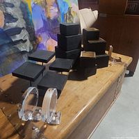 Black display boxes in various sizes arranged on a wooden chest, some with lids off.