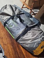 Photo of the REI Half Dome 2+ tent rolled and secured with black straps, showing the product label and packaging.