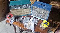 Wide shot of all items on table including two hardware organizers and various small bags of nuts, bolts, washers, and fasteners
