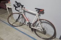 Full drive-side view of white Dawes Lightning 1500 road bicycle with drop handlebars and red accents