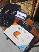 Roll-up case with multiple fountain pens, Waterman box, mesh cup, Speck case on wooden surface
