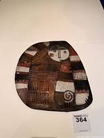Front view of ceramic cat wall plaque showing abstract cat design with textured pattern and earth tone colors.