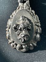 Close-up front view of the Victorian style carved pendant showing detailed roses and leaves design on an oval base with ornate floral border.