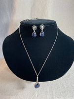Photo showing the necklace on a black velvet bust with matching blue stone earrings above it.