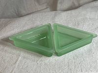 Two triangular jadeite glass bowls positioned side by side on a light fabric surface showing their top and inside surfaces to highlight shape and color.