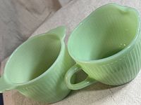 Close-up view of Fire King creamer and sugar cup showing light green ribbed textured pattern and shapes.