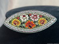 Front view of marquise-shaped vintage Italian mosaic brooch with ornate multicolor floral pattern and brass edge.
