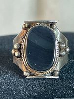 Close-up front view of vintage sterling silver ring with black onyx stone and silver bead accents.