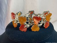 Front view of the vintage Coro Lucite leaf bracelet showing the red, orange, and yellow translucent Lucite leaves on a silver-tone metal linked base.