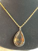 Close-up of the pendant showing its teardrop-shaped brown faceted stone set in sterling silver bezel.