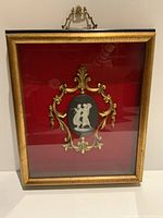 Front view of the gilt frame with brass detail and porcelain medallion.