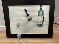 Frontal view of framed watercolor painting with water bottle for scale