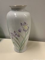 Front angled view showing hand-painted purple iris flowers and gold rim on white porcelain vase
