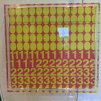 Frontal image of the large square acrylic pop art prototype with lime green background and pink oval and numbers pattern in front of white wall, showing gloss and some surface reflections.