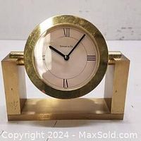 Front view of the vintage Tiffany & Co. brass desk clock showing the round clock face with Roman numerals and the brass tilt frame.