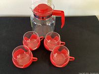 Full set including coffee pot and four matching cups arranged on a black surface