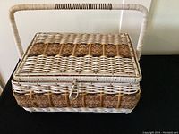 Closed wicker sewing basket with white and natural wicker, tan detail, and handle.