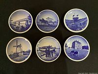 Six 3.25-inch Royal Copenhagen decorative plates with blue and white scenic designs arranged on black fabric.