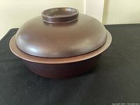 Side angle view of the brown covered casserole dish showing the base and lid with a central knob.