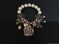 Front view of Betsey Johnson bracelet showing rose charm, heart charm, purple stones, green leaves, bows, and pearls.