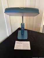 Blue Day-Light Sky light therapy lamp, powered off, showing design and adjustment arm with instruction manual below.