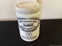 Front view of Dundee milk glass orange marmalade jar with black printed text and original lid.