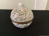 Closed view of the covered bowl showing the strawberry-shaped finial on the lid and gold-accented floral openwork design.