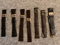 Front view of seven leather watch straps aligned side by side, showing different colors and price tags.