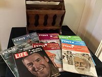 Wooden magazine rack with magazines displayed in front showing covers