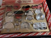 Full view of the Mirro toy set in original packaging showing pots, lids, aluminum pieces and muffin tin.