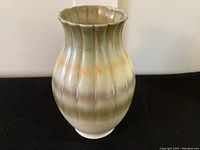 Front view of vintage ceramic vase with green and orange glazed fluted design.
